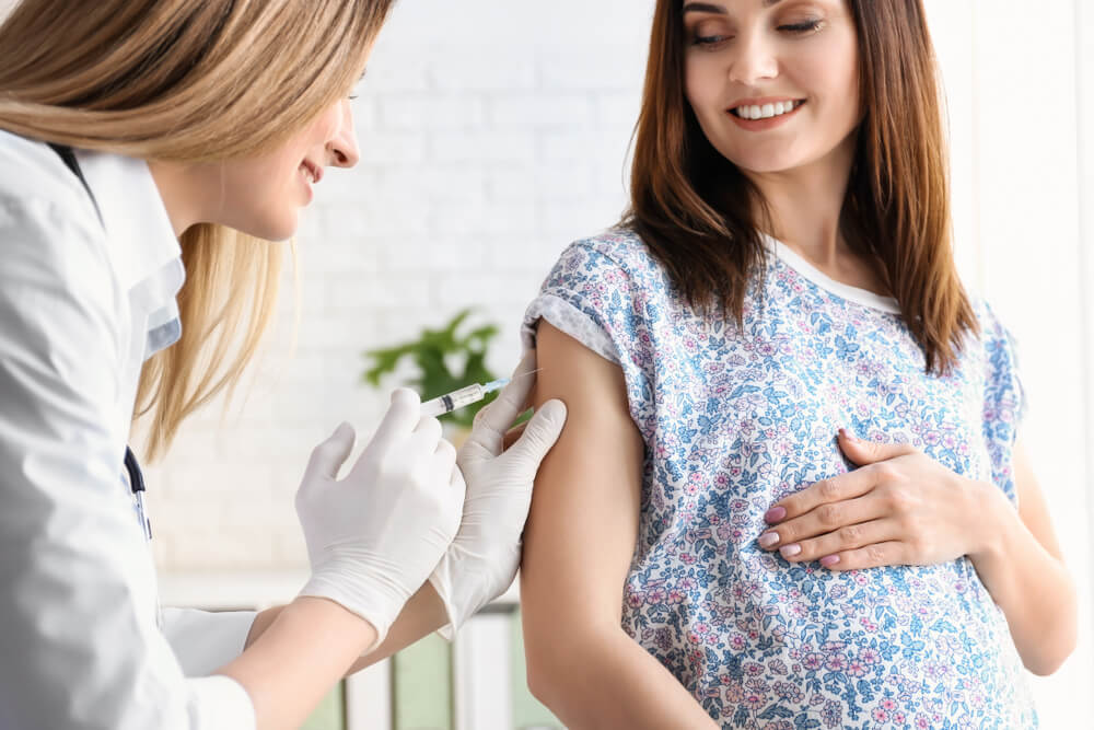 Médico vacunando a una mujer embarazada en una clínica