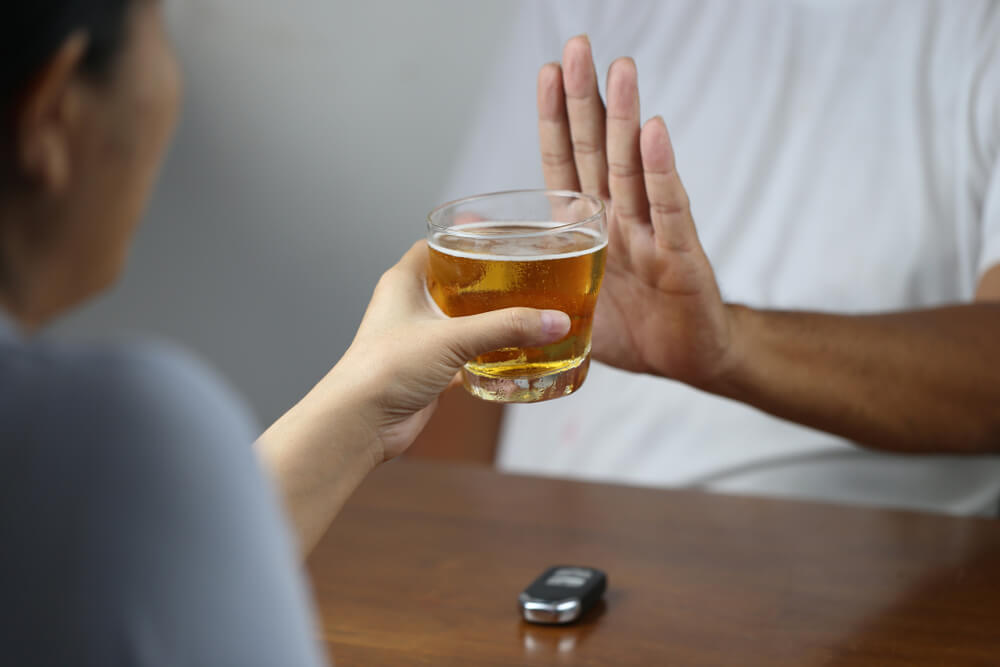 Hombre rechazando un vaso de bebida con la mano
