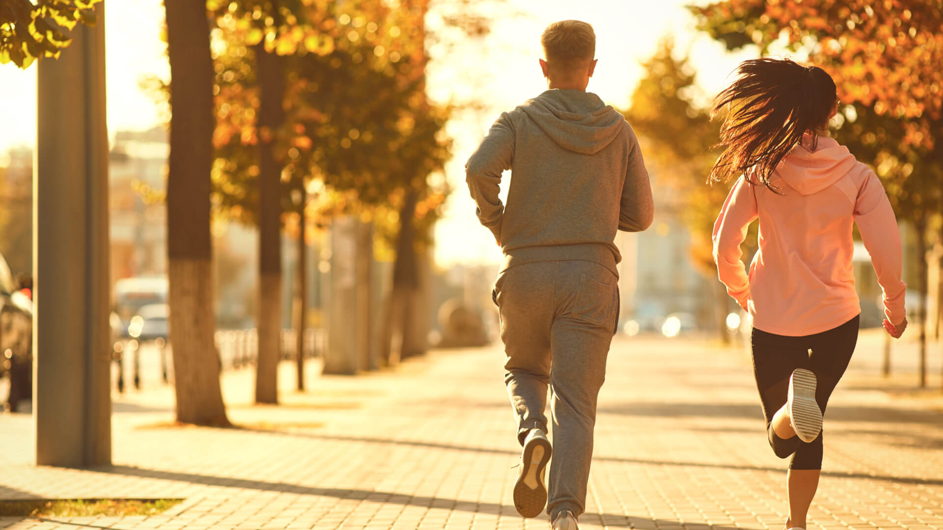 Un hombre y una mujer corren por las calles de la ciudad por la mañana.