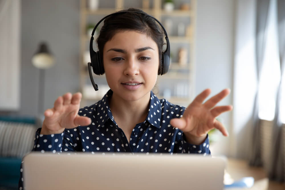 Joven empresaria con un auricular está en una videollamada por la computadora