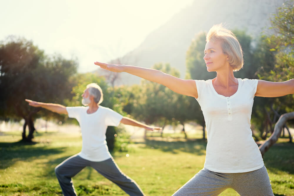 Pareja de ancianos haciendo yoga en el parque