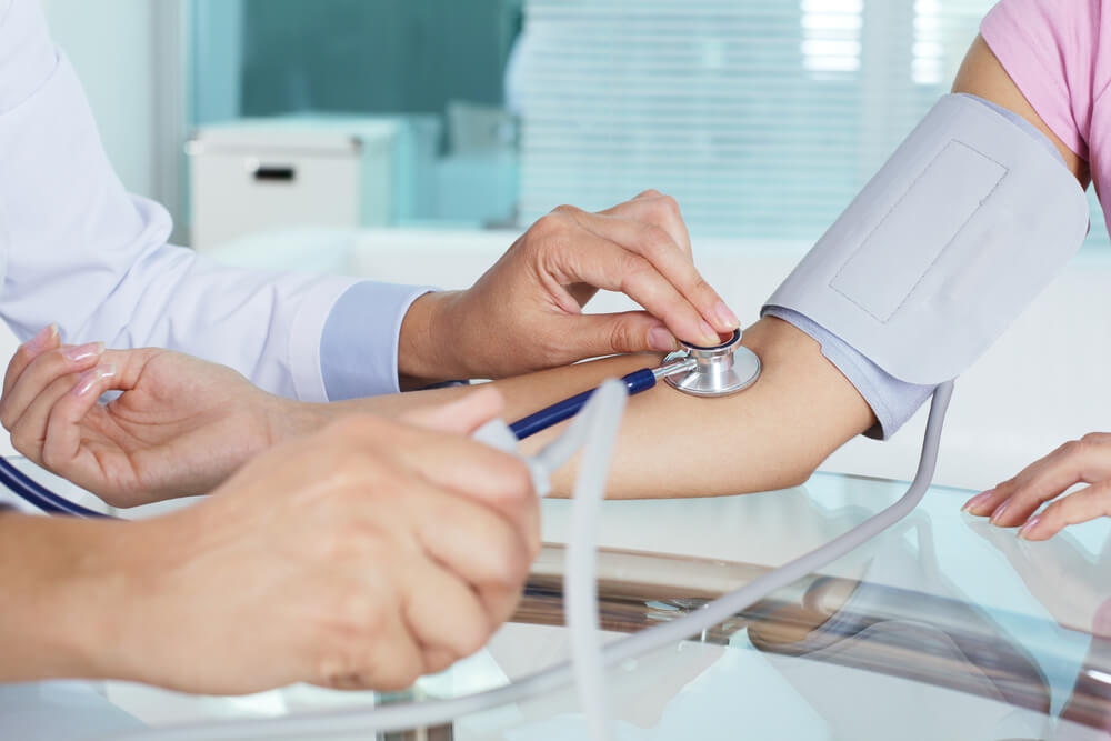 Médico midiendo la presión de un paciente en una consulta