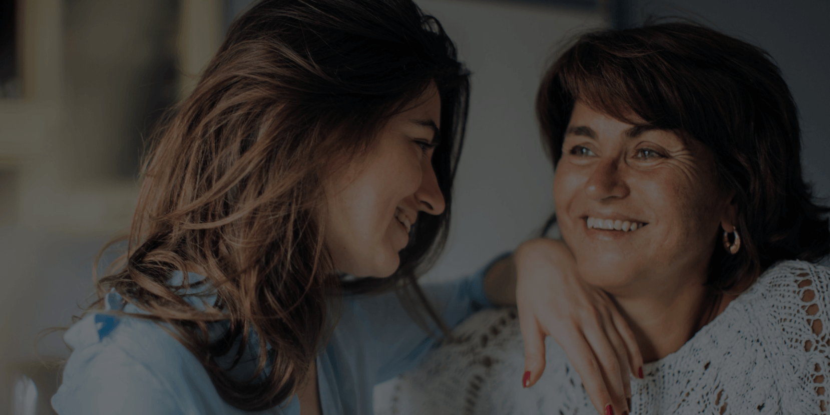 Dos mujeres sonriendo mientras se miran.